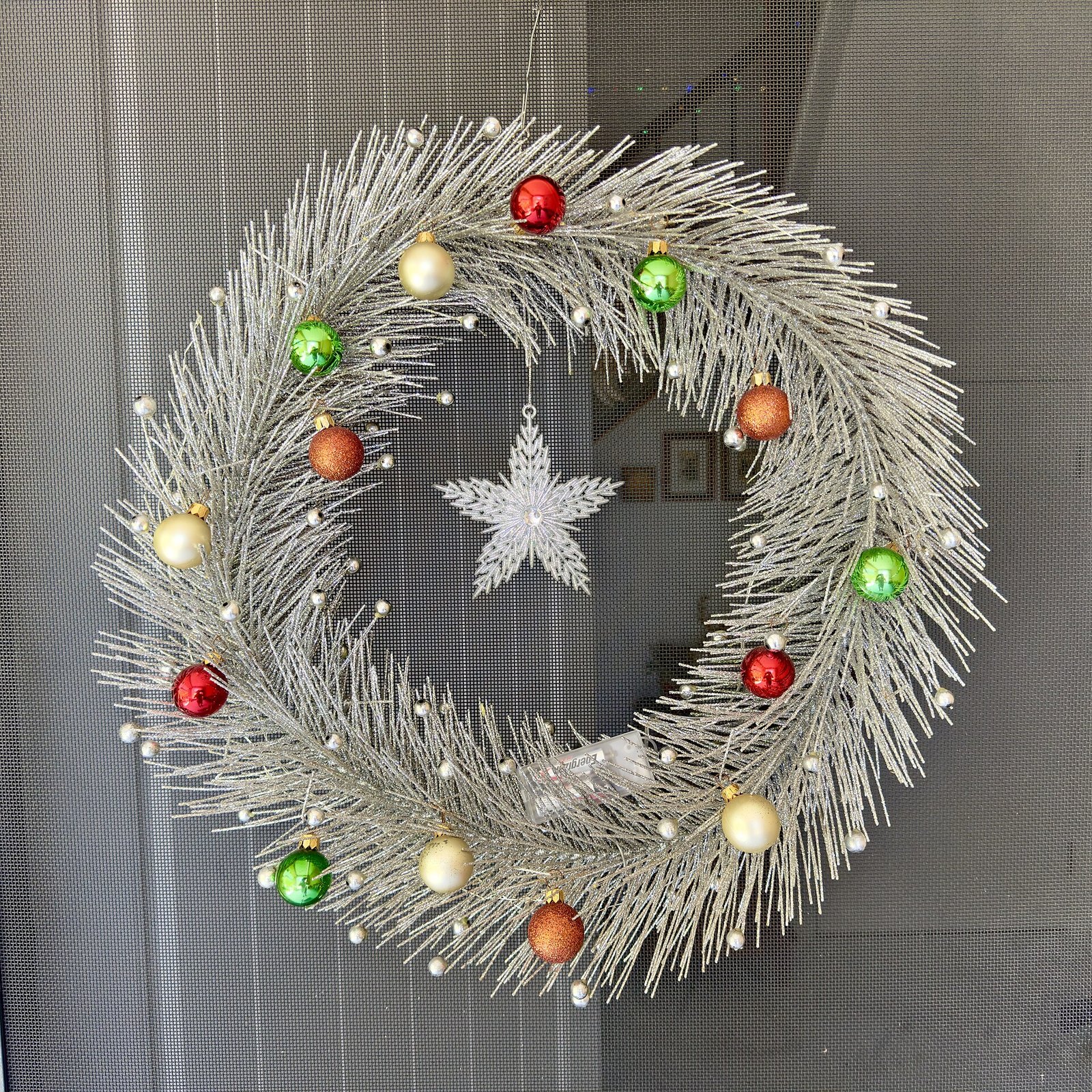 A silver Christmas wreath with red, green and gold baubles hanging on a house door — what size wreath for a front door